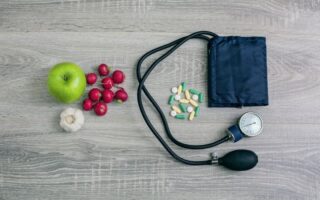 A blood pressure cuff, pills, Cherries, and a green apple
